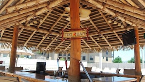 Un bar tiki con techo de paja y pilares de madera.