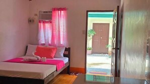 A bedroom with a bed, a bedside table, a window with curtains, and a door leading outside.