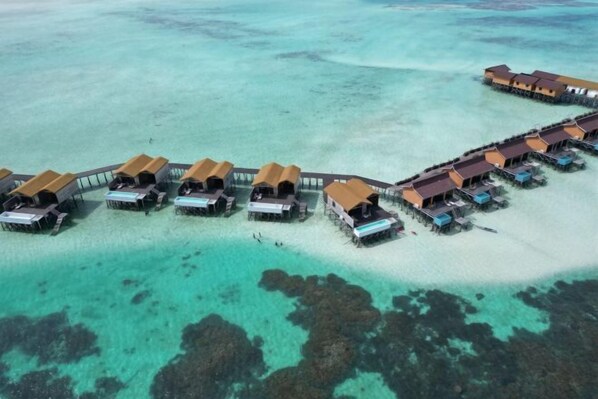 An aerial view of overwater bungalows with clear turquoise water and rocky seabed. - Moana Water Village Semporna (Semporna)