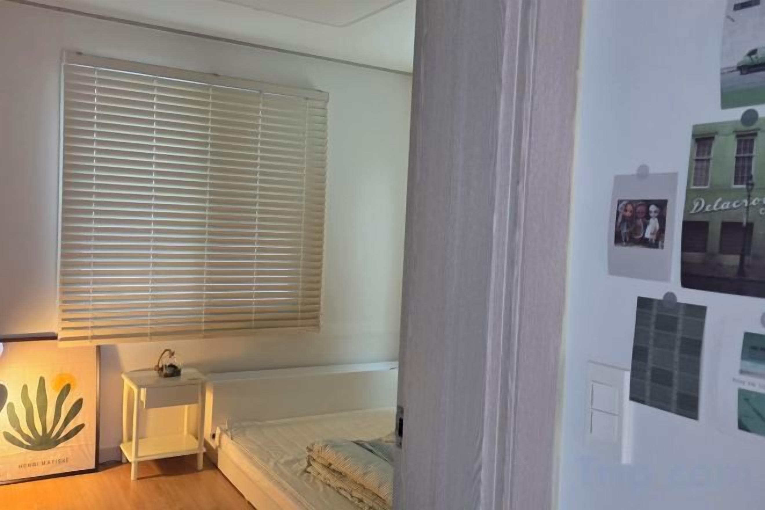 Quarto com cama, mesa de cabeceira, luminária e detalhes decorativos na parede.