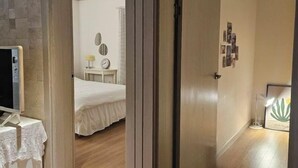 Un dormitorio con cama, mesita de noche, lámpara y una pared decorada con marcos.