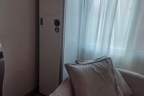 A room with a bed, a window with sheer curtains, and a door with a control panel. - JeJuHahastay (Jeju)