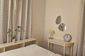 A bedroom with a bed, a bedside table with a lamp, and wall-mounted clocks. - JeJuHahastay (Jeju)