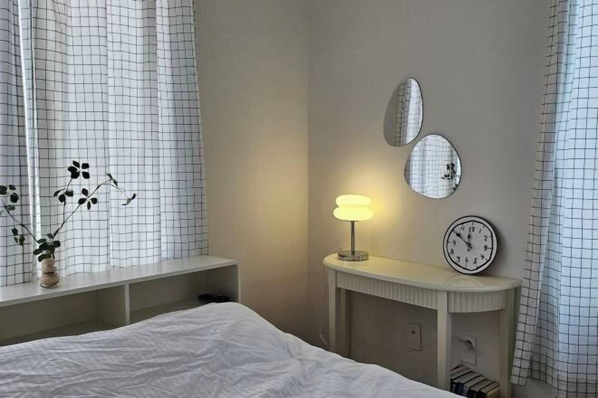 Une chambre à coucher avec un lit, une table de chevet, une lampe et des horloges murales.