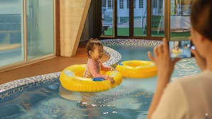 A child in a pool with inflatable rings, a tiled edge, and a view of a building outside. - Beyand Private Pool Villa Pension, Daebu (Ansan)