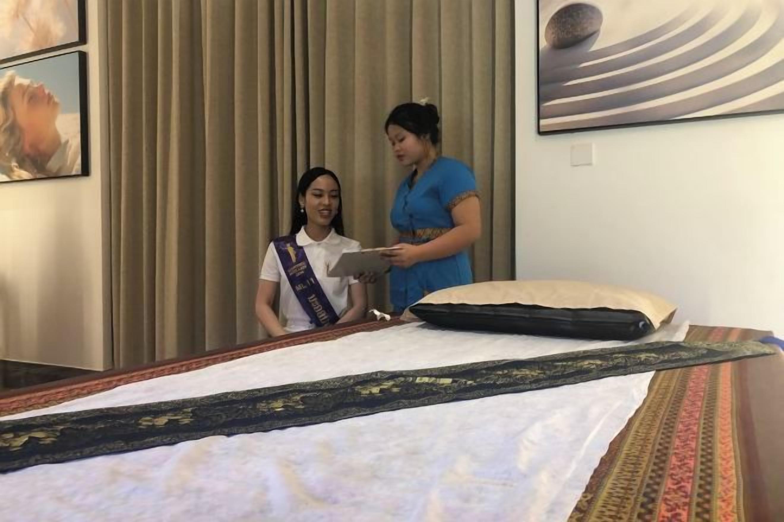 A hotel room with a bed, a pillow, a blanket, and a wall with a painting.