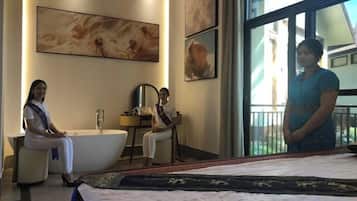 A hotel room with a bathtub, a bed, and a large window.