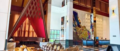 A lobby with a checkered floor, a reception desk, and a large decorative wall.