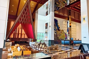 A lobby with a checkered floor, a reception desk, and a large decorative wall.