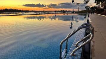 An infinity pool with a clear view of the sunset and distant landscape.