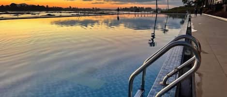 An infinity pool with a clear view of the sunset and distant landscape.