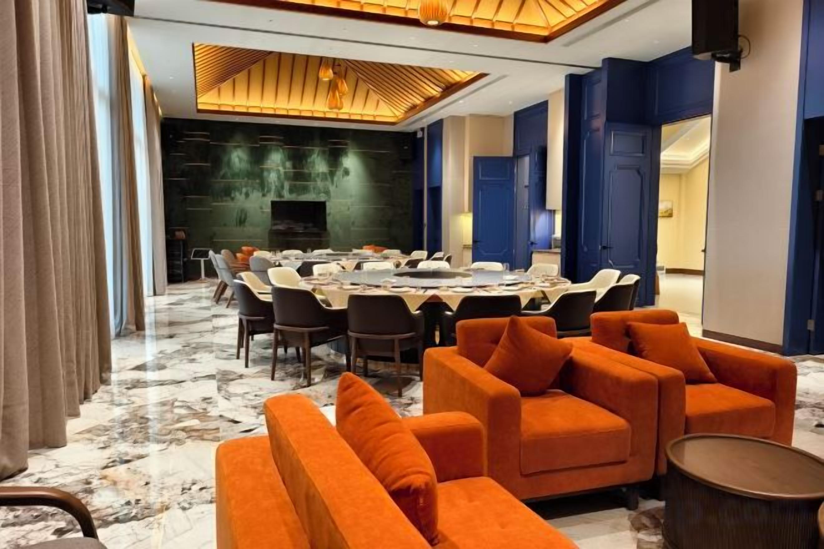 A modern conference room with a large oval table, orange sofas, and a fireplace.