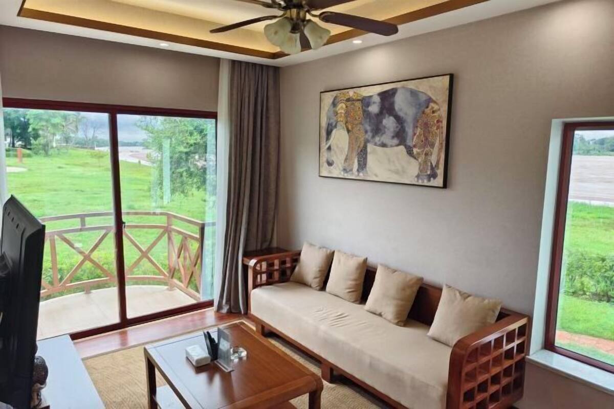 A living room with a sofa, a coffee table, a TV, and a painting of a cow.