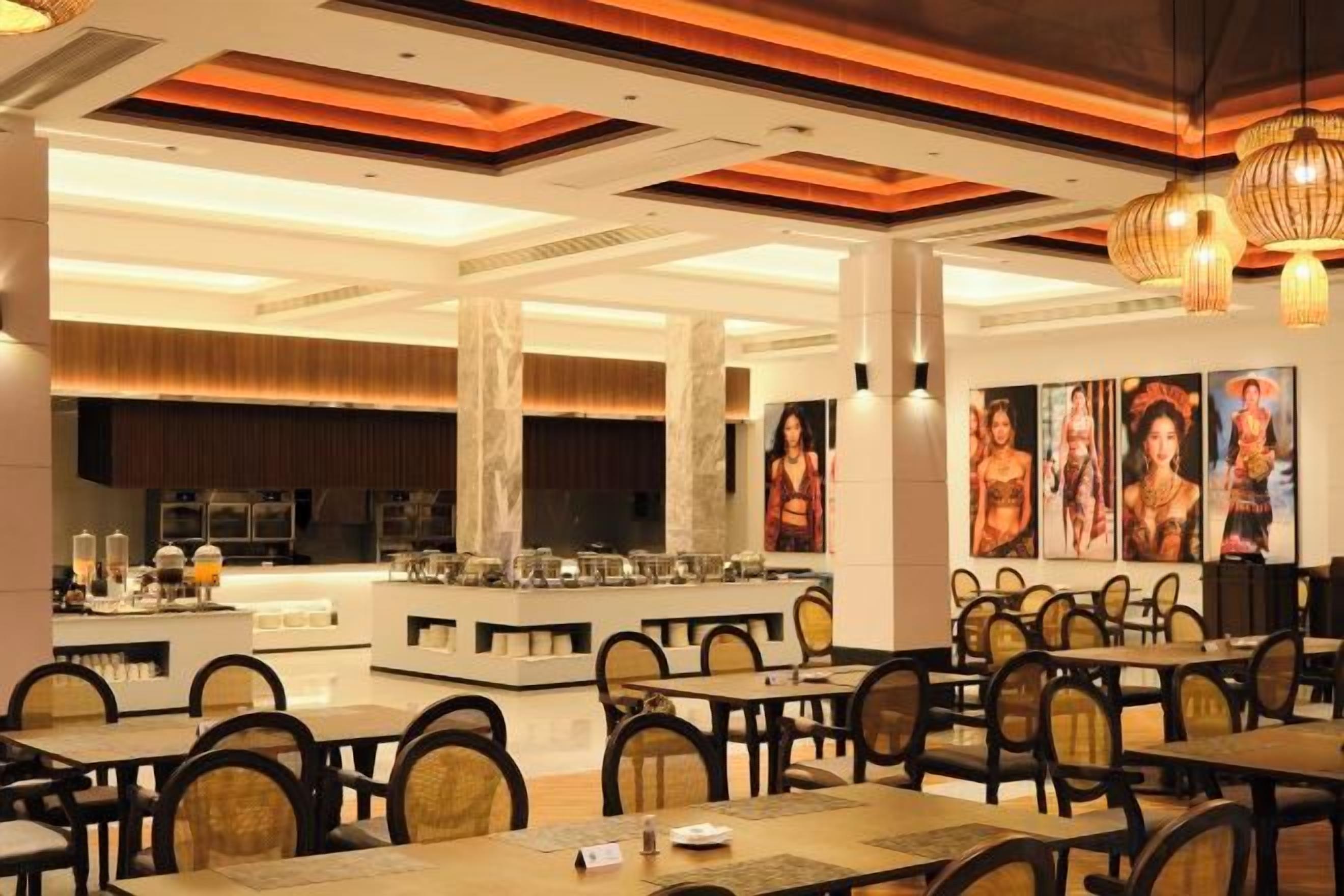 A restaurant with multiple dining tables and chairs, a central bar area, and artwork on the walls.