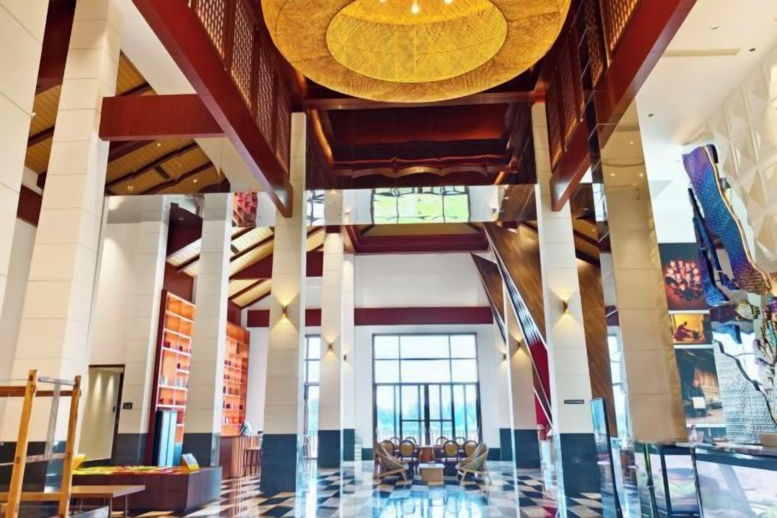 A spacious lobby with high ceilings, a checkered floor, and a central seating area.