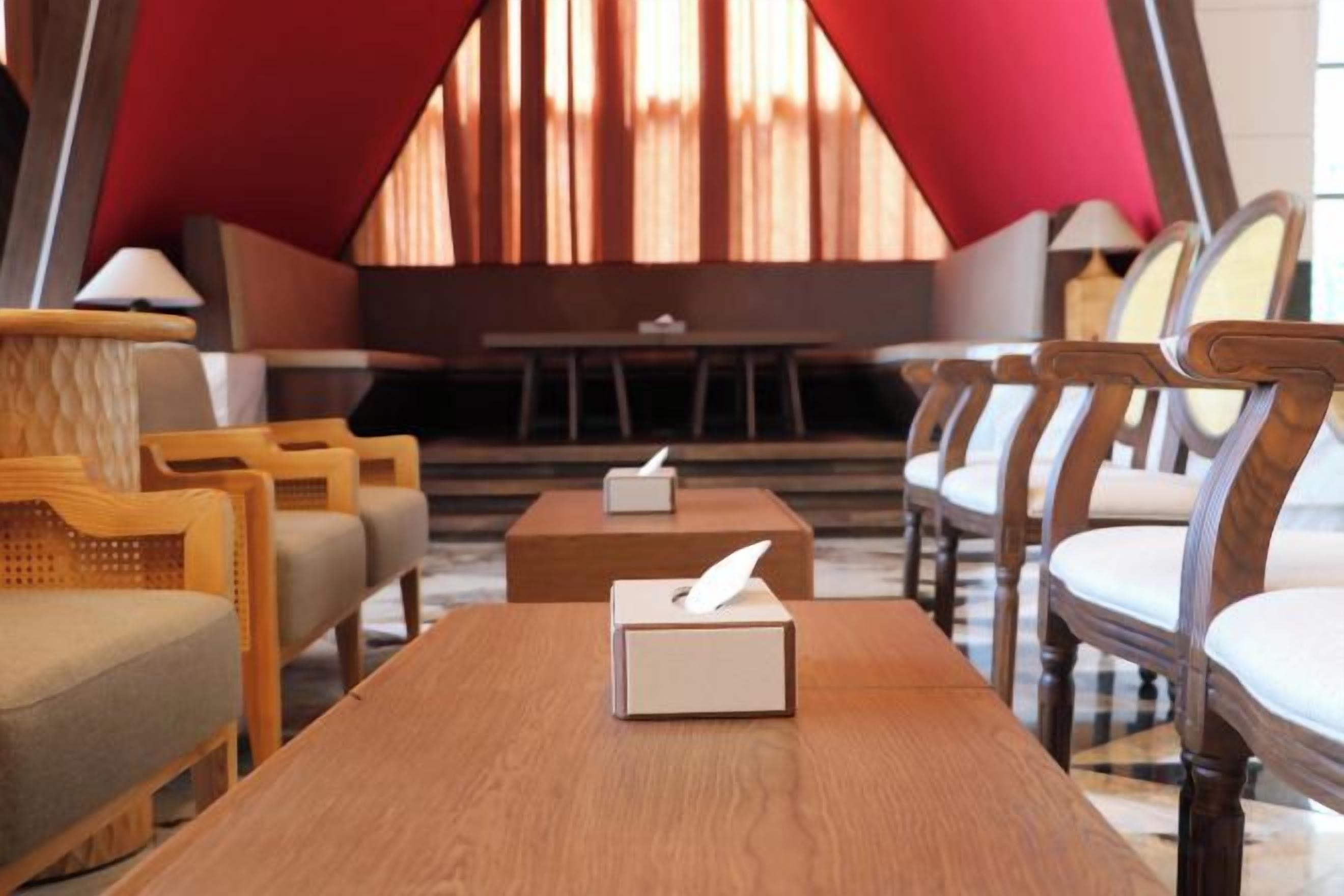 Un hall d’hôtel comprenant un comptoir d’accueil, un espace salon et une grande fenêtre avec des rideaux.