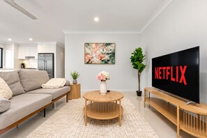 Ein modernes Wohnzimmer mit einer Couch, einem Couchtisch, einem Fernseher und einem Bild an der Wand.