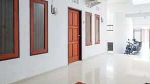 A hallway with a wooden door, a window, and a scooter parked in the distance. - KoolKost near Raya Canggu (Minimum Stay 5 Nights) (Bali)