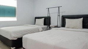A hotel room with two single beds, a window, and a black metal rack. - KoolKost near Raya Canggu (Minimum Stay 5 Nights) (Bali)