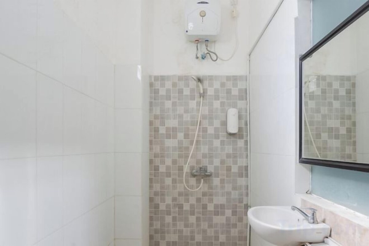 A bathroom with a tiled shower wall, a sink, and a mirror.