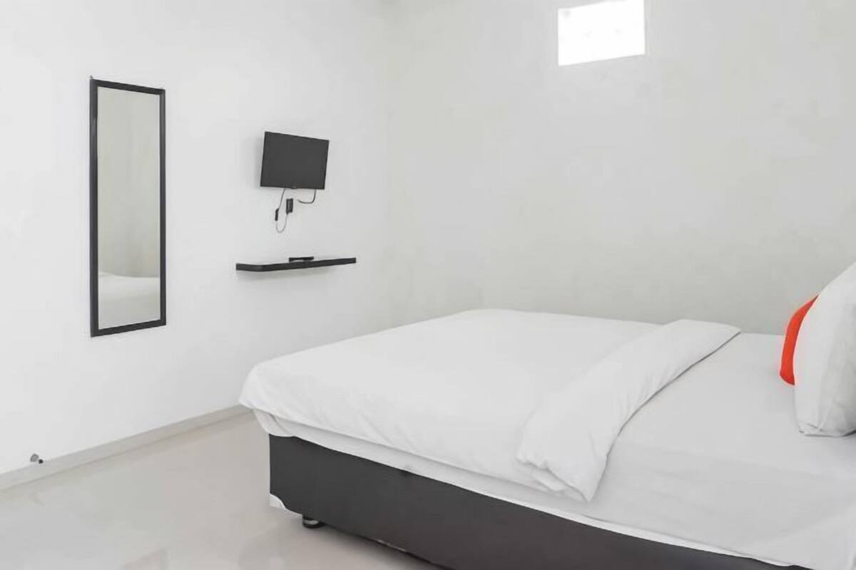 A modern bedroom with a bed, a TV mounted on the wall, and a mirror.