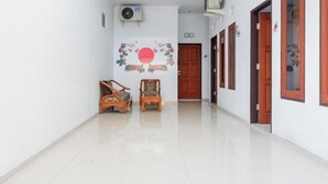A hallway with two wooden chairs, a wall-mounted air conditioner, and a door at the end. - KoolKost near Raya Canggu (Minimum Stay 5 Nights) (Bali)
