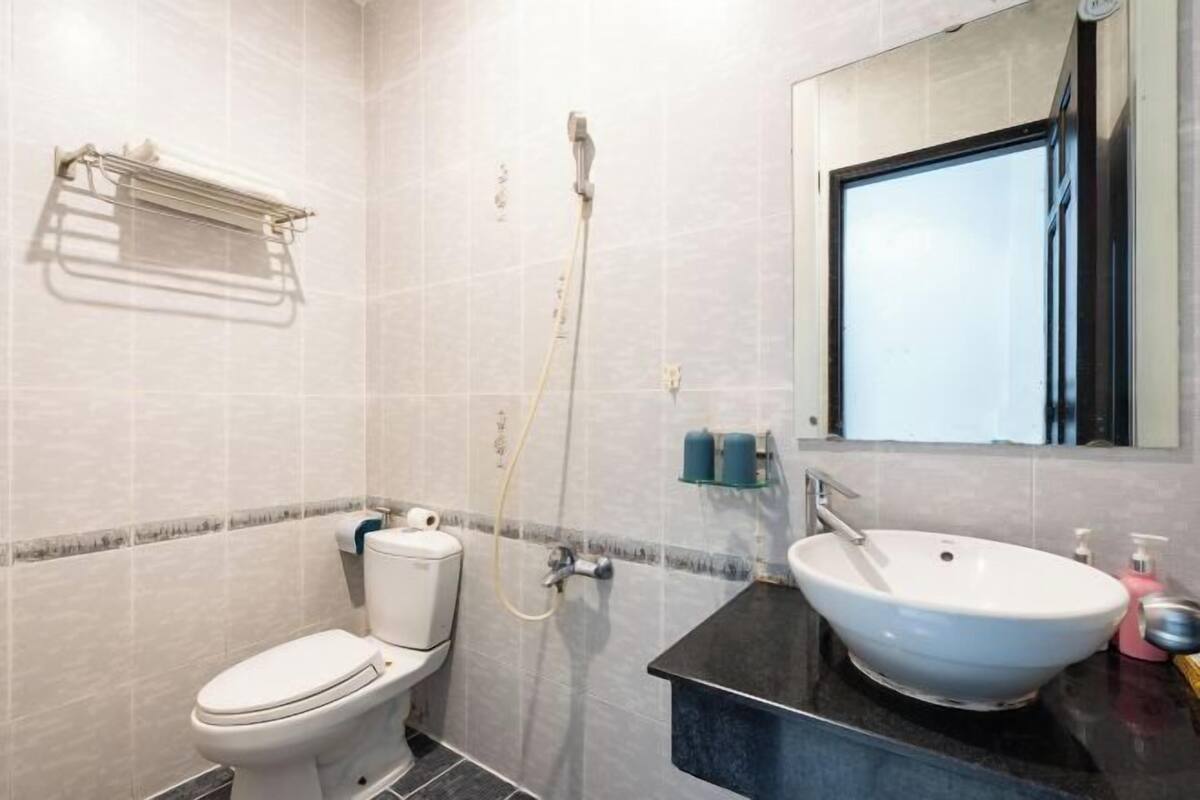 A bathroom with a toilet, a sink, a shower, and a towel rack.