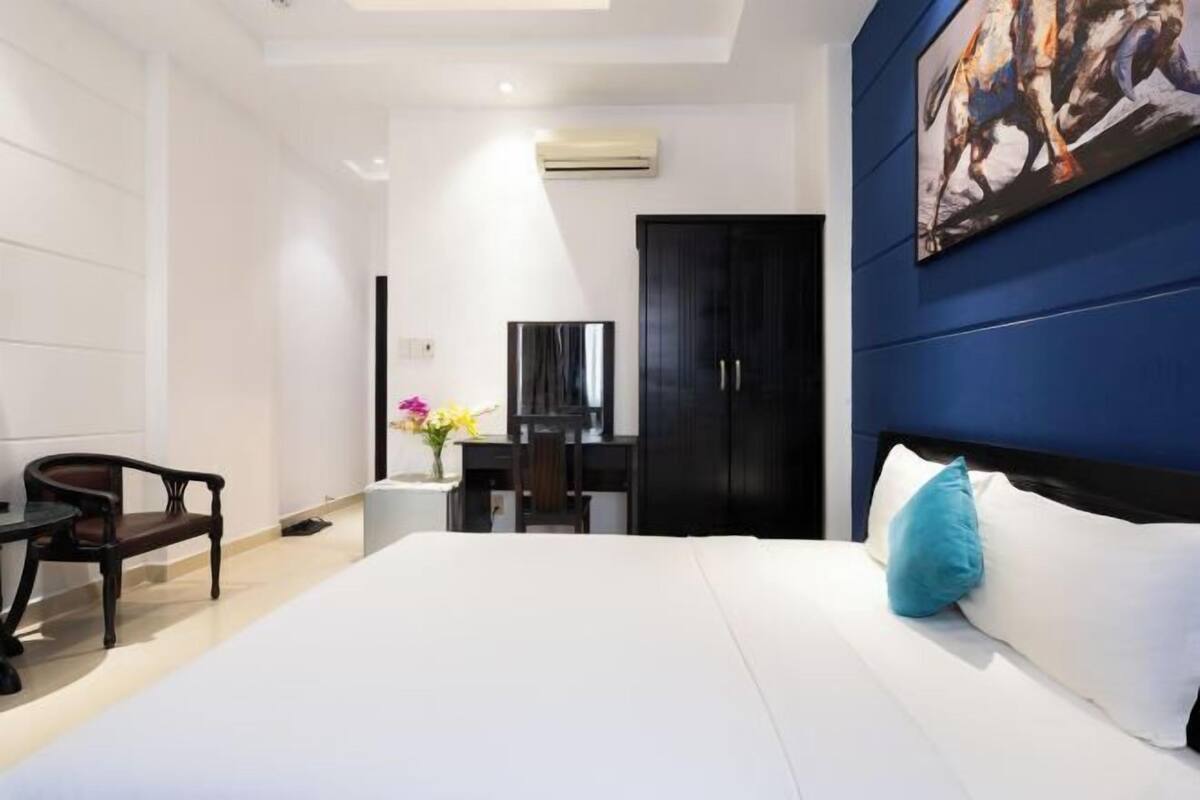 A hotel room with a bed, a desk, a chair, a TV, and a wardrobe.