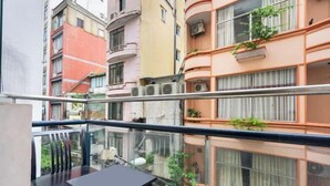 Ein Balkon mit Tisch und Stühlen, mit Blick auf ein mehrstöckiges Gebäude mit Balkonen und Pflanzen.