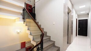 Eine moderne Treppe mit Glastrennwand, die zu einer Zwischenebene mit einem roten Schild führt.