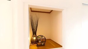 Un pequeño rincón bien iluminado con un florero y un estante decorativo.