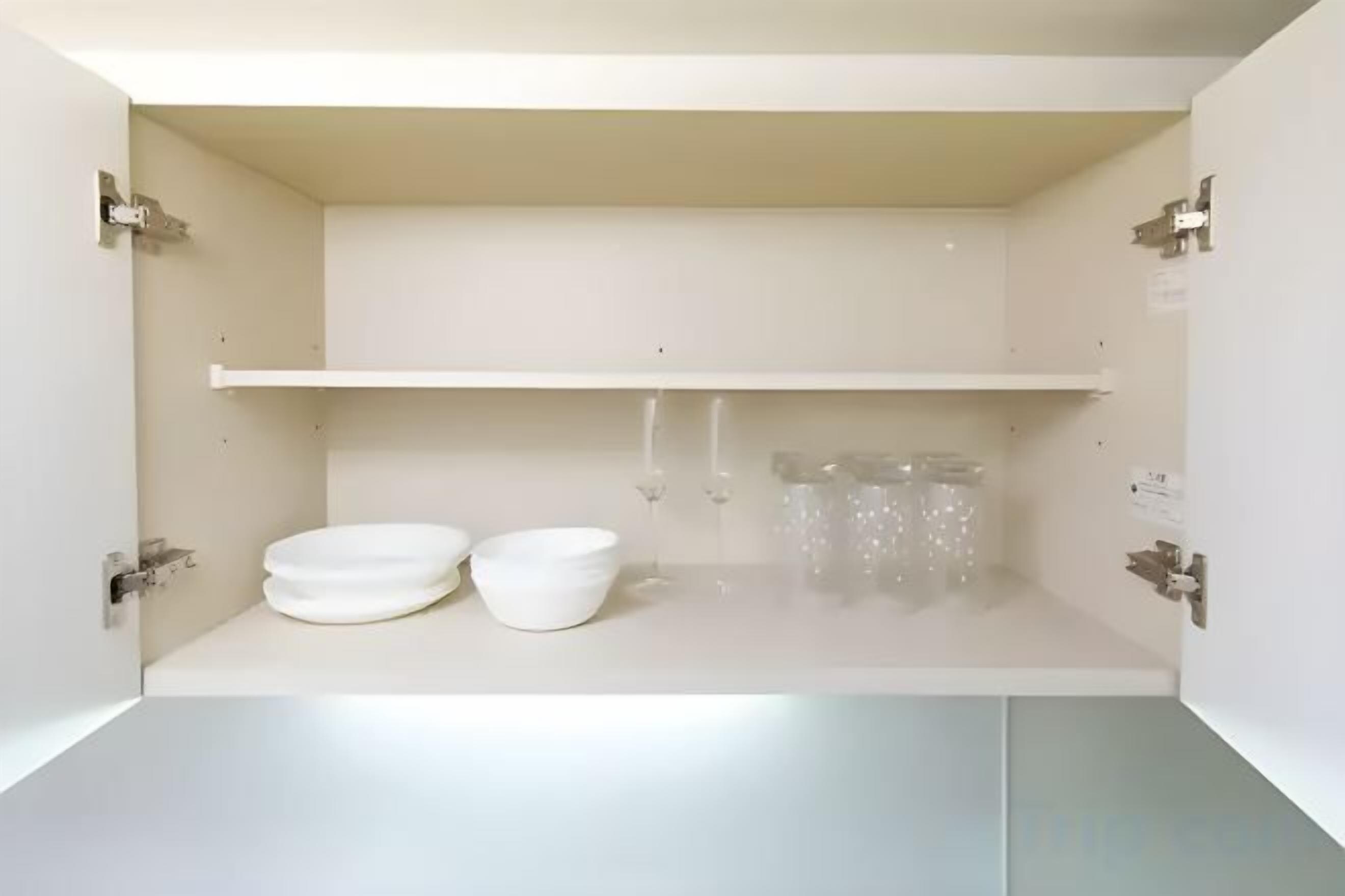 Un armadietto bianco con due ciotole e un recipiente di vetro.