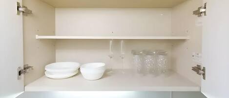 Un armadietto bianco con due ciotole e un recipiente di vetro.