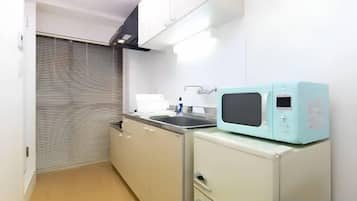 A compact kitchen with a microwave, sink, and cabinets.