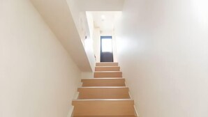 Una escalera conduce a una puerta al final de un pasillo con paredes lisas.