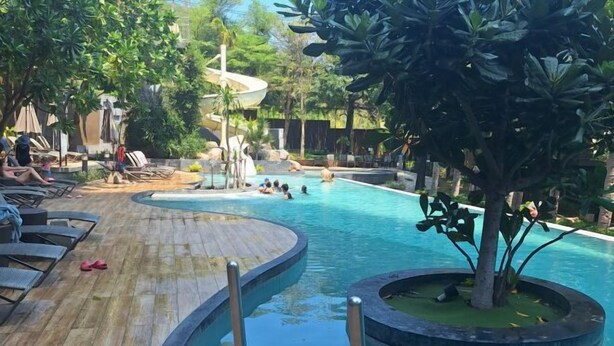 A pool area with lounge chairs, a wooden deck, and a water slide. - unixx Seaview Resort (Pattaya)