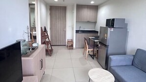 A compact kitchen with a dining area, a sofa, and a TV. - unixx Seaview Resort (Pattaya)