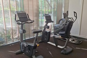 Two stationary bikes in a room with large windows and blinds. - unixx Seaview Resort (Pattaya)