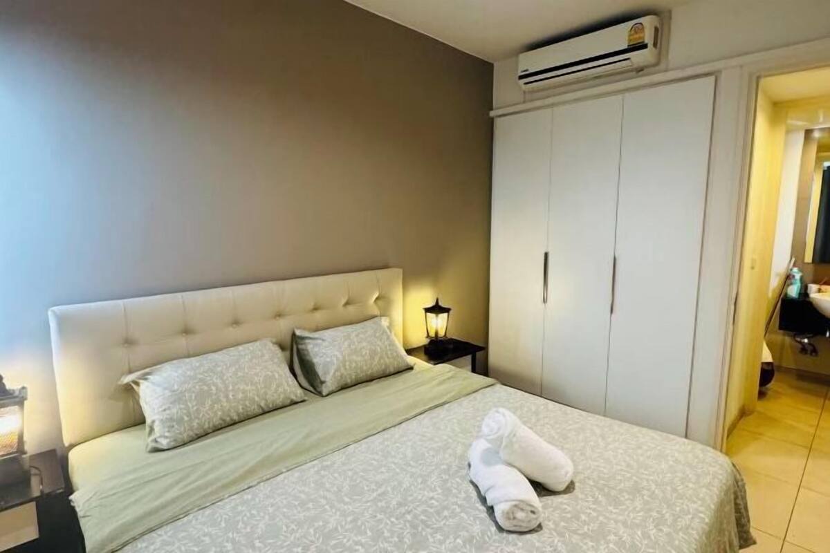 A bedroom with a bed, a nightstand, an air conditioning unit, and a wardrobe.