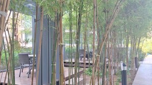 An outdoor area with bamboo plants, wooden deck, and outdoor seating. - unixx Seaview Resort (Pattaya)