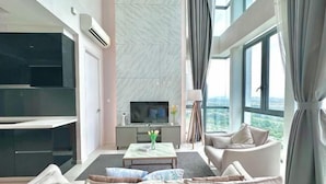 A modern living room with a sofa, a coffee table, a TV, and a view of the outdoors. - Elysia Park Medini by Stayrene near Legoland (Iskandar Puteri)