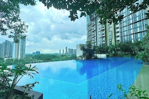 A rooftop infinity pool with a city view, surrounded by greenery and modern buildings. - Elysia Park Medini by Stayrene near Legoland (Iskandar Puteri)
