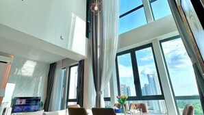 A modern hotel room with a dining area, large windows, and a city view. - Elysia Park Medini by Stayrene near Legoland (Iskandar Puteri)