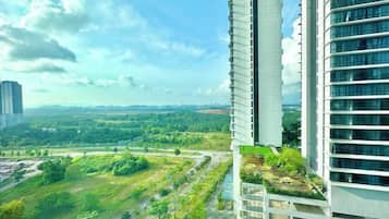 Um edifício alto com vários andares, um jardim no terraço e vista para uma paisagem verde com árvores e uma estrada.