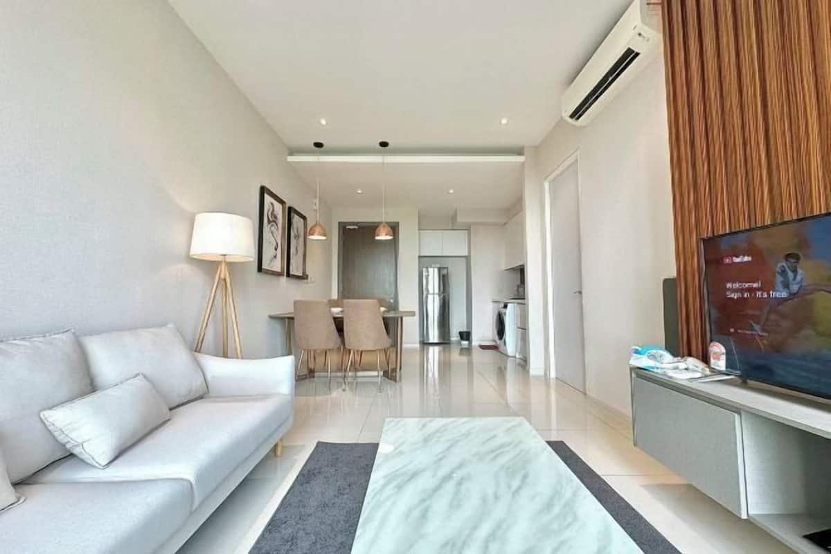 A modern living room with a sofa, a coffee table, a TV, and a dining area with chairs and a table.