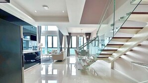 A modern interior with a glass staircase, a seating area, and a view of the outdoors. - Elysia Park Medini by Stayrene near Legoland (Iskandar Puteri)