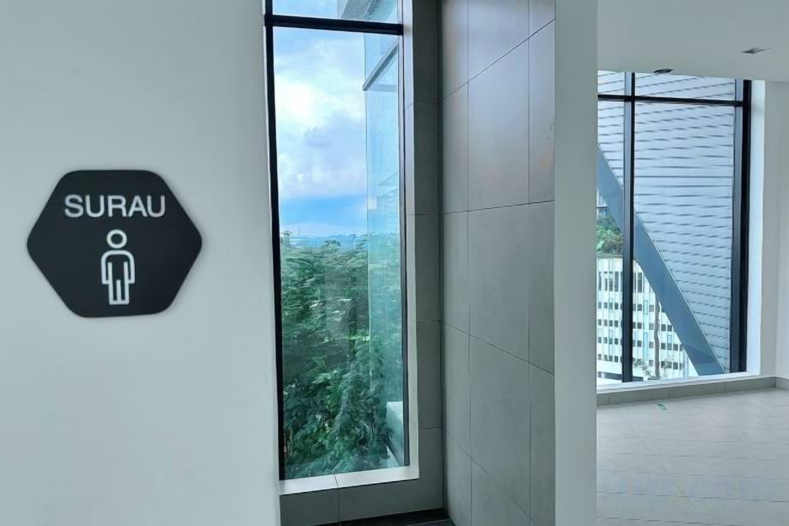 A modern interior with a large window, a sign indicating a men's restroom, and a view of buildings outside.