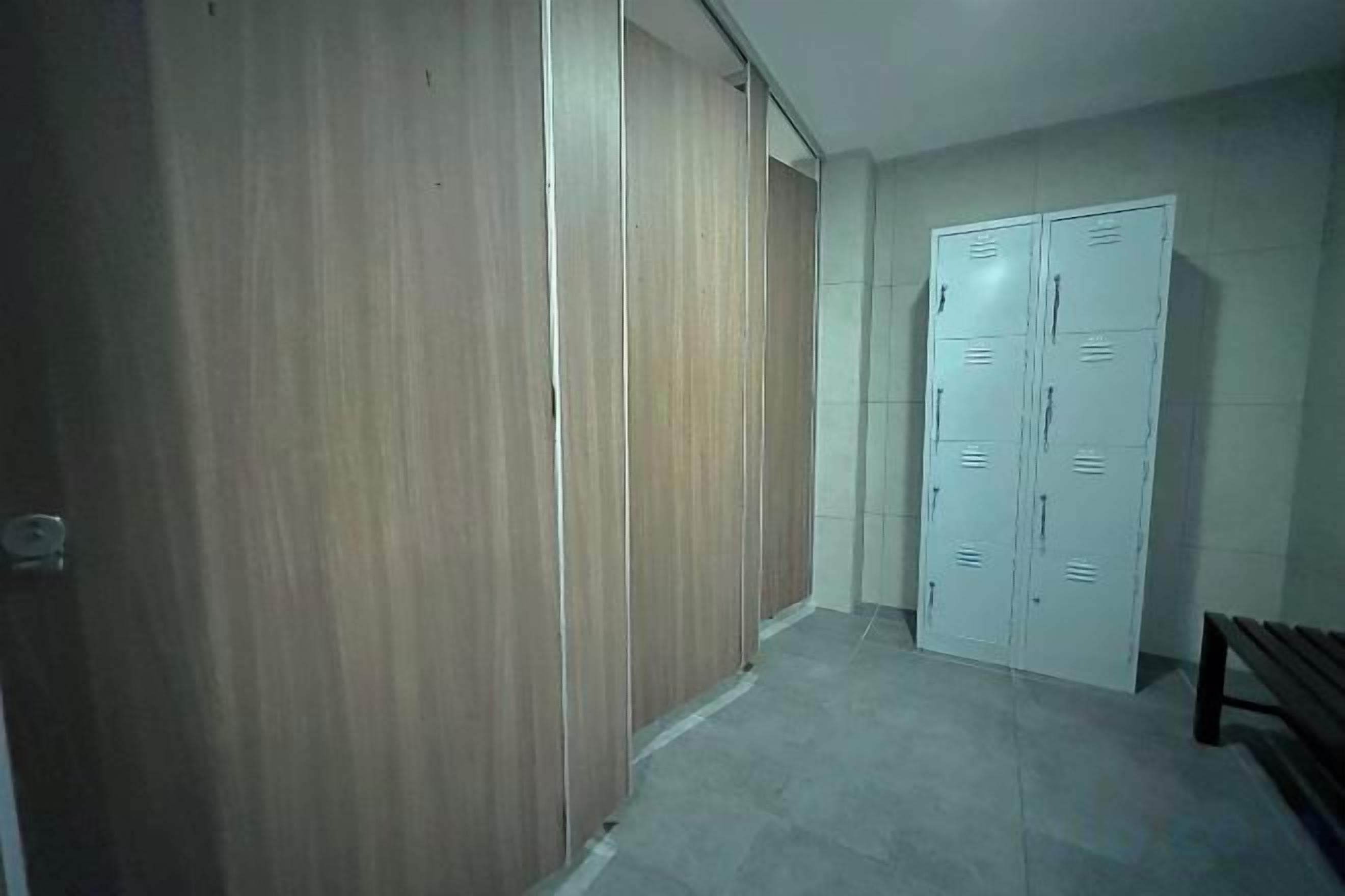 A hallway with a wooden wardrobe and a white door with multiple locks.