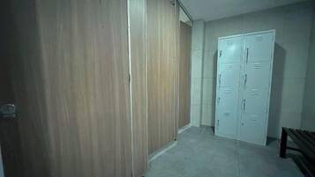 A hallway with a wooden wardrobe and a white door with multiple locks.