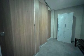 A hallway with a wooden wardrobe and a white door with multiple locks. - Elysia Park Medini by Stayrene near Legoland (Iskandar Puteri)